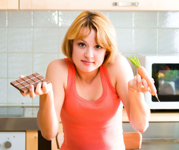 Young woman with carrot and chocolate