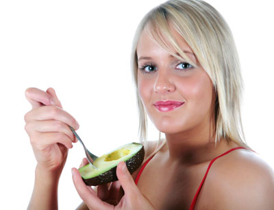 Young woman eating fresh Avocado