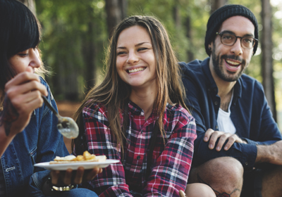 Friends camping while eating bean dish