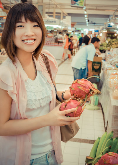 Young woman with dragon fruits at the super-marktet