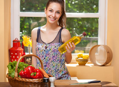 Woman in kitchen with a olive oil bottle in hand