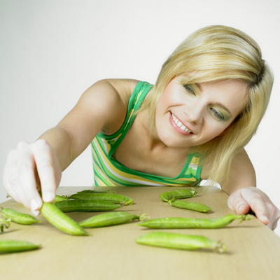 Woman with pod peas on table