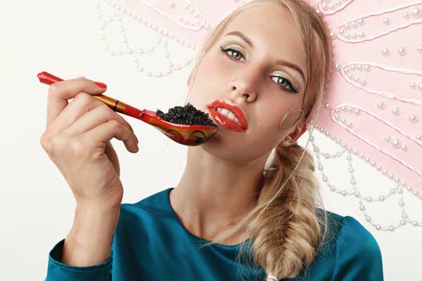 Beautiful young woman eating fresh caviar